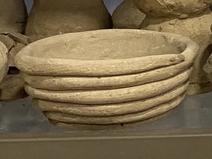 Stack of shallow hand-built clay bowls on Alali's shelf