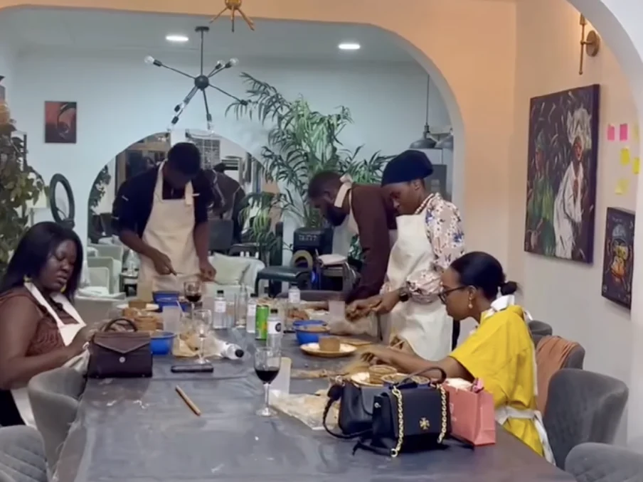 Guests making pottery together around a long table at Alali, with paintings and plants behind them