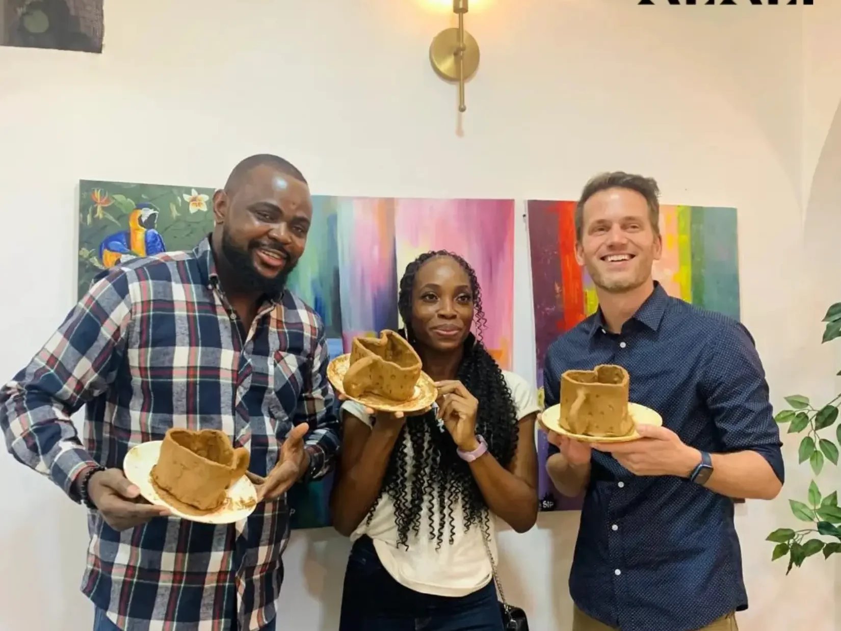 Guests at Alali Studio in Victoria Island, Lagos, holding their hand-built clay cups and plates in front of colourful paintings