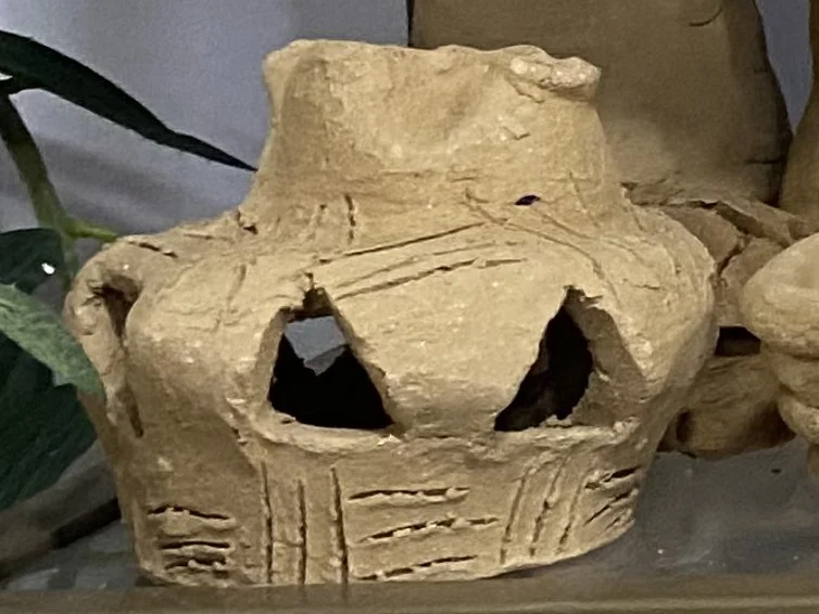 Hand-built clay lantern with triangular openings on Alali's shelf