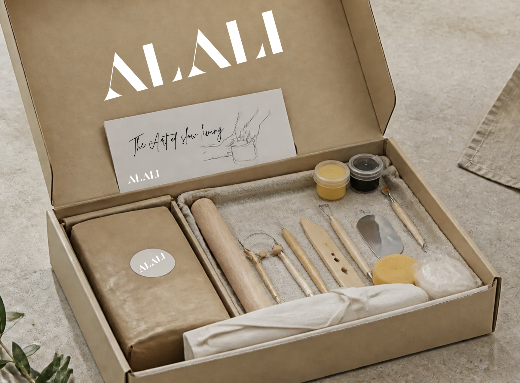 Inside The Alali Clay Box: 2kg of clay, pottery tools, SPNL paint and a guide in a linen-lined box