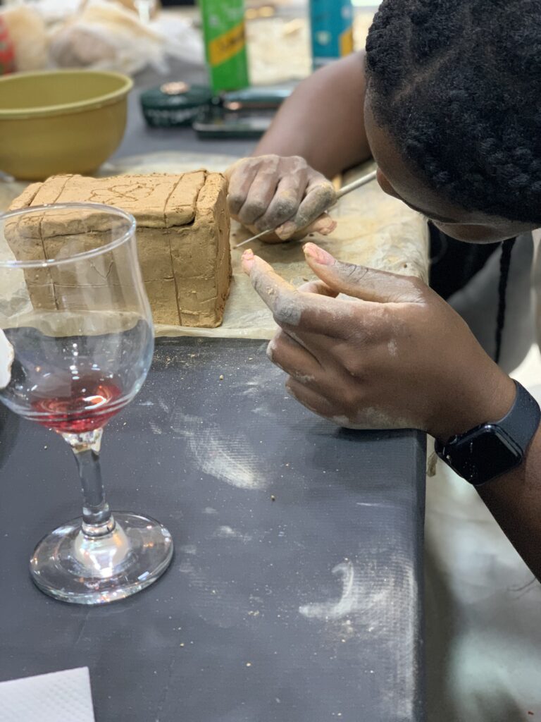 A guest adding detail to a hand-built clay piece at Alali