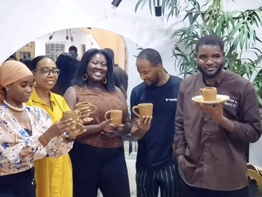 Five guests at Alali holding up their hand-built clay mugs and a cup on a plate
